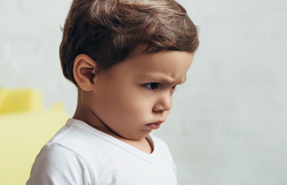 Young child with angry expression on their face, soft focus background